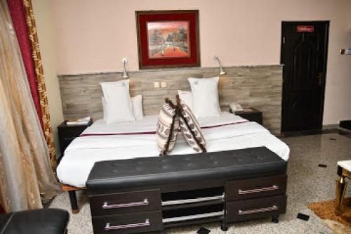 贝宁城Room in Lodge - Choice Gate Hotel-Business Double的一间卧室配有一张大床和木制床头板