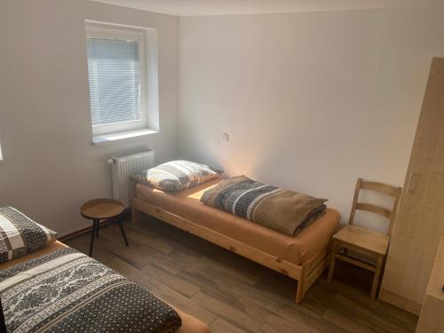 Mariánské RadčicePenzion Norden的客房设有两张床、一把椅子和窗户。