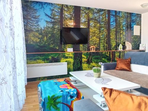 别拉什尼察Apartman "AROMA 1"Bjelasnica的客厅设有大窗户和森林壁画