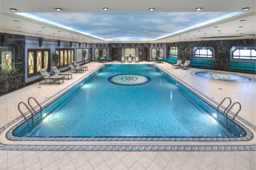 吉达华尔道夫吉达酒店 - 卡斯尔夏克的酒店的大型游泳池配有桌椅