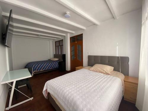 卡哈马卡Casa Hospedaje Cajamarca的一间卧室配有一张床、一张书桌和一台电视