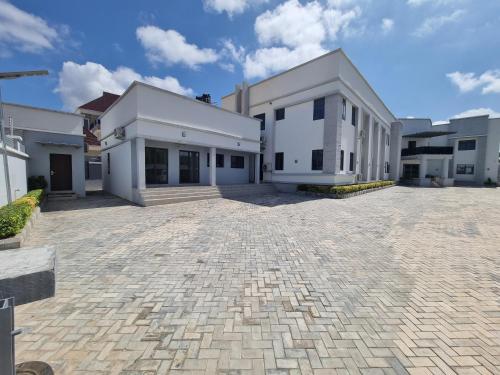 MaiduguriSolace Suites and Homes Maiduguri的一座大型白色建筑,有砖车道