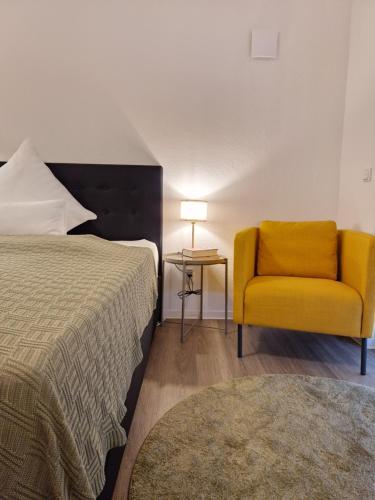 比勒费尔德Stadt-Appartement am Nordpark的一间卧室配有一张床和一张黄色椅子