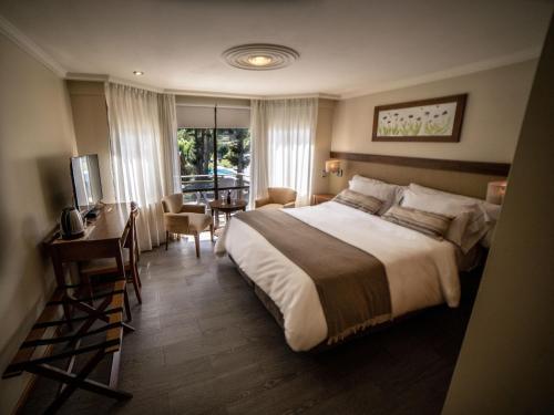 拉安戈斯图拉镇Resort de montaña - La Comarca的酒店客房设有一张大床和一张书桌。