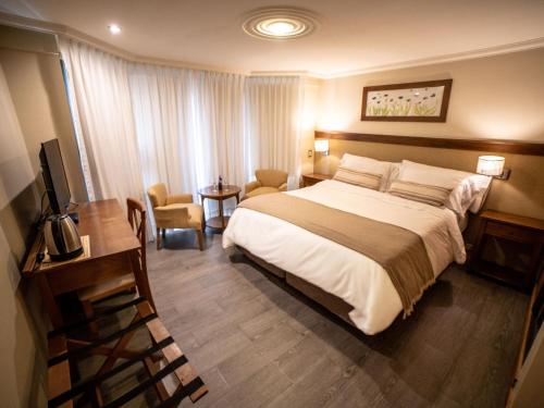 拉安戈斯图拉镇Resort de montaña - La Comarca的酒店客房设有一张大床和一张书桌。