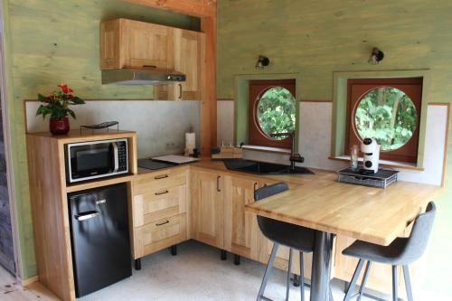 Frasnes-lez-AnvaingEntre mare et chêne的厨房配有木桌和黑冰箱。