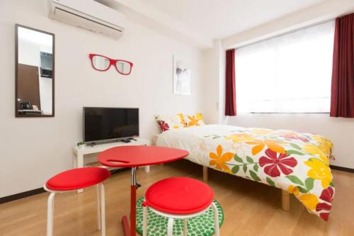 大阪幸运经济型酒店的一间卧室配有床和两张红色的桌子