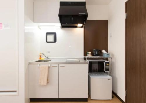 大阪幸运经济型酒店的白色的厨房配有水槽和微波炉