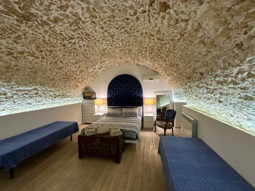 锡拉库扎菊苣度假屋的一间卧室设有两张床和石墙