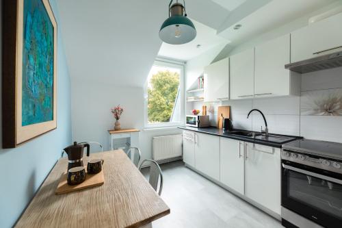 库多瓦-兹德鲁伊Family Apartment - Centrum的厨房配有白色橱柜和木桌