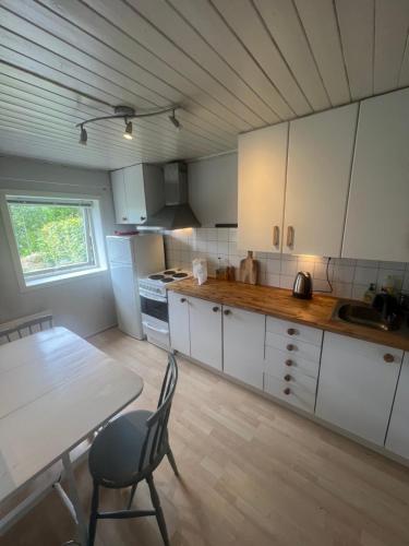 卑尔根Cosy apartment with free parking的厨房配有白色橱柜、桌子和桌椅
