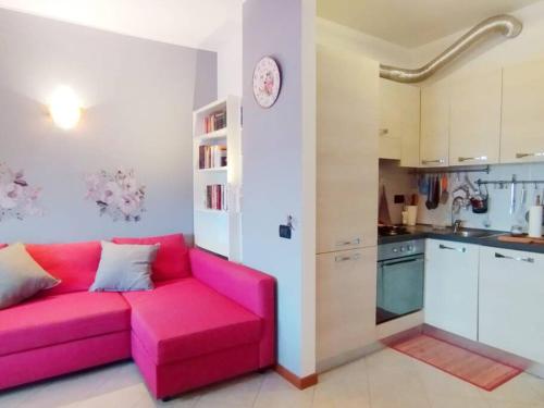 布斯托阿西齐奥il Sole di Busto APT的客厅设有粉红色沙发,厨房设有