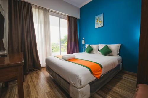 斯勒曼Villa Prambanan Jogja with Private Swimming Pool by Simply Homy的一间设有蓝色墙壁和窗户的床的客房