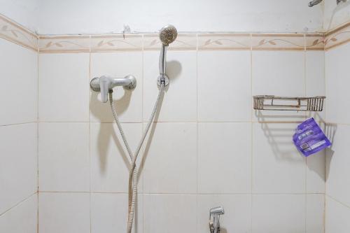 勒吉安Gana Inn Legian的白色瓷砖浴室内的淋浴头