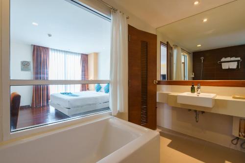 曼谷Lantana Resort Hotel Bangkok的带浴缸、水槽和镜子的浴室