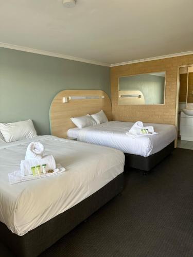 土乌巴三叶草酒店的酒店客房,配有两张带毛巾和镜子的床