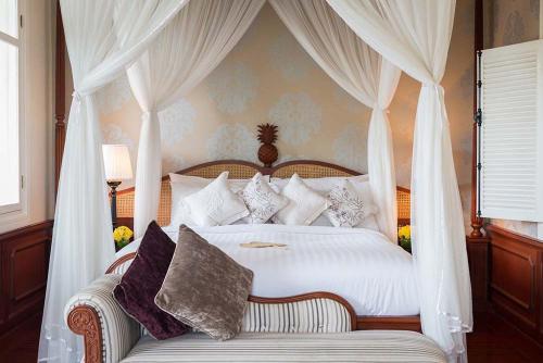 琅勃拉邦露塞公寓式酒店的卧室配有带枕头的白色天蓬床