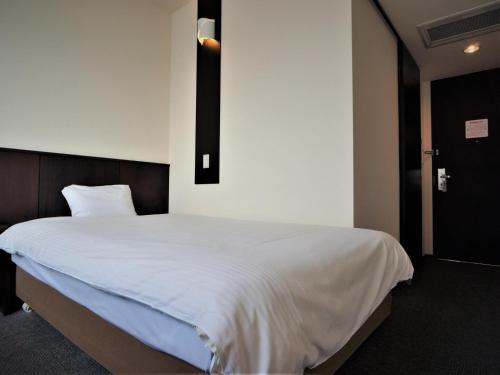 鸟栖市绿色丰富鸟栖站前酒店的一间卧室配有一张带白色床单的大床