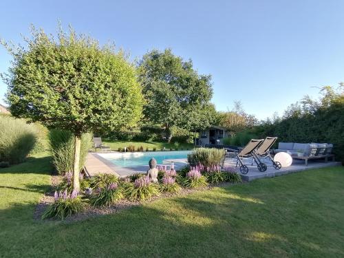 洛维涅LE CLOS DU MONTYS的后院,带一个种有树木和鲜花的游泳池