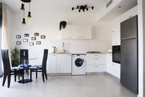 特拉维夫Space age Jaffa Apartment的白色的厨房配有洗衣机和桌子