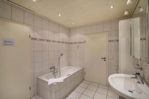 博特罗普mit Wintergarten nah Moviepark的白色的浴室设有浴缸和水槽。