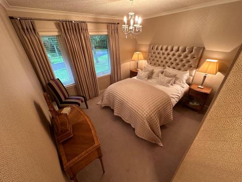 奥赫特拉德One Dunbar Court Gleneagles Village的一间卧室配有一张床、一把椅子和一个吊灯。