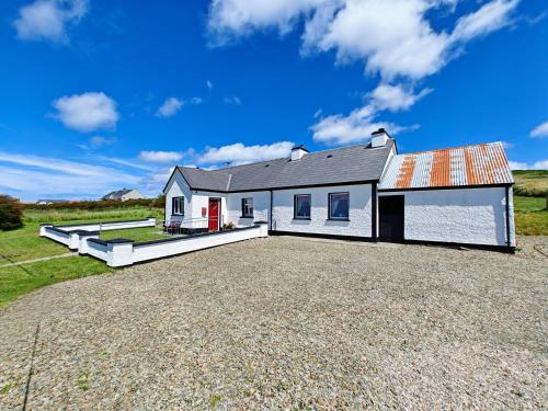 马林Teach Róisin-Traditional Irish holiday cottage in Malin Head.的车道上墓地的房子