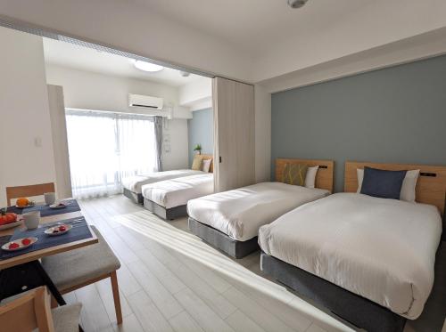 大阪ESLEAD HOTEL Namba Daikokucho的酒店客房设有两张床和一张桌子。