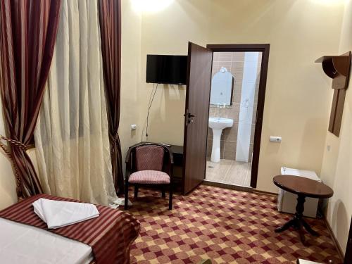 埃里温亚美尼亚皇宫酒店的酒店的客房 - 带一张床和一把椅子以及一间浴室