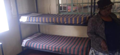 内罗毕Kioneki hostels的一个人站在带两张双层床的房间
