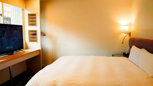 台北Hub Hotel Banqiao Branch的卧室配有白色的床和电视。