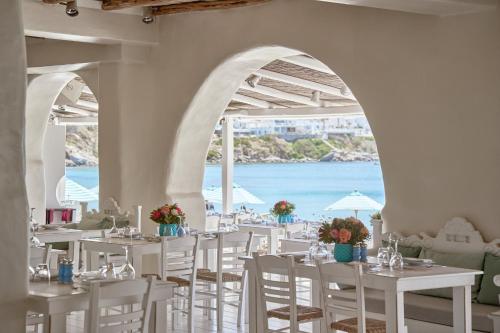 萨鲁Nammos Hotel Mykonos的餐厅设有白色的桌椅,享有海景。