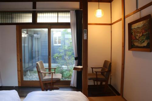 高山宿川之中的鱼旅馆的一间卧室配有一张床、两把椅子和一个窗户