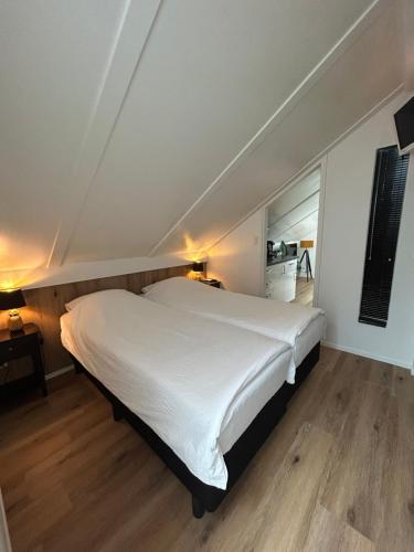 登堡Boetje 51的卧室配有一张白色的大床,铺有木地板
