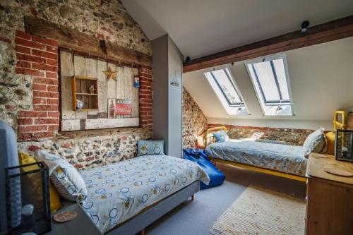 小沃尔辛厄姆Cog Cottage的一间卧室设有两张床和砖墙