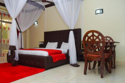 姆特瓦帕White Peacock Resort Mtwapa的一间卧室配有一张带红色毯子和椅子的床