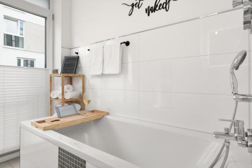 埃森Golden-Loft 92qm, zentral & ruhig, Messe I HBF nah的带浴缸的白色浴室和架子上的笔记本电脑
