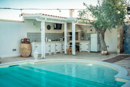 塔维亚诺VILLETTA NEL VERDE CON PISCINA a 5 MINUTI DA GALLIPOLI的后院的游泳池,带有厨房和房子