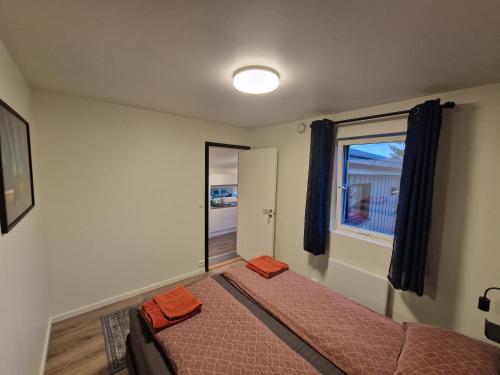 特罗姆瑟Northern living 1 room with shared bathroom的一间卧室配有带橙色床单的床和窗户。