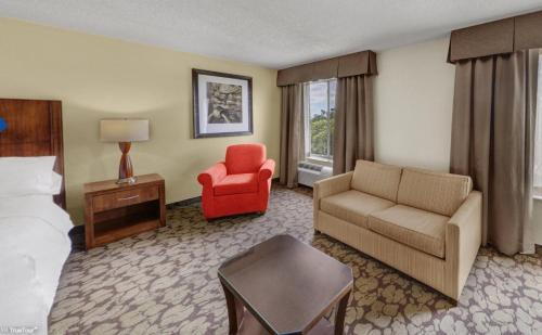 坦帕Hilton Garden Inn Tampa East Brandon的酒店客房配有床、沙发和椅子