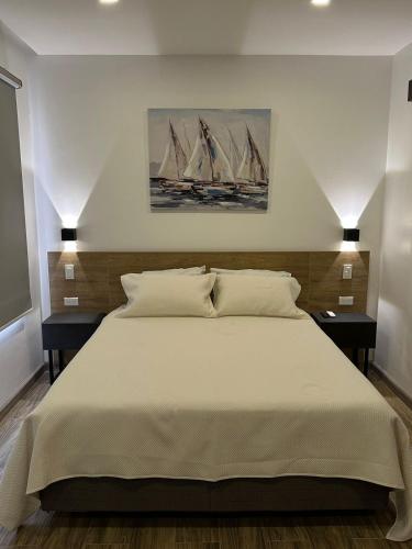 瓜亚基尔Kiran Lodging Guayaquil的一间卧室配有一张带2个床头柜的大型白色床