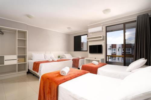 弗洛里亚诺波利斯Boulevard Beach Canasvieiras Hotel的酒店客房设有三张床和电视。