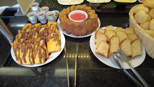 贝洛奥里藏特安东尼奥卡洛斯司多普酒店的柜台上三盘食物,包括面包和糕点