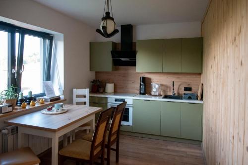 LaskowaMiętowe Zacisze Zator的厨房配有绿色橱柜和桌椅