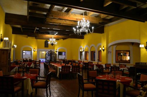 圣胡安特奥蒂瓦坎Villas Arqueologicas Teotihuacan的一间设有桌椅的餐厅,位于拥有黄色墙壁的房间
