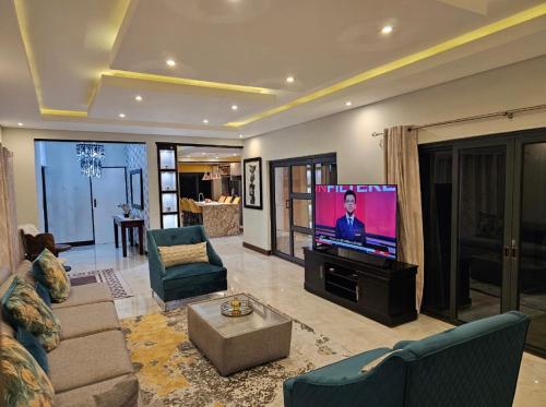 卢萨卡Chuumba Villas的客厅配有电视、沙发和椅子