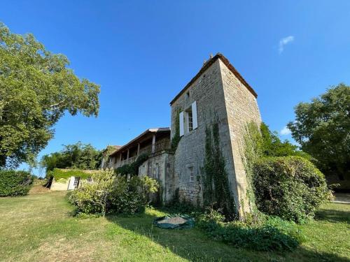 DuravelChâteau la Gineste - Castle and Vineyard的一座老砖房,在田野上常有常春藤