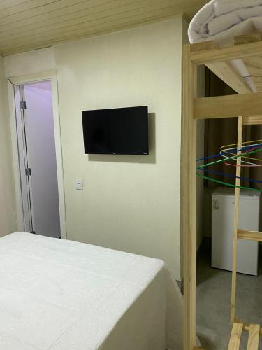 沙帕达-杜斯吉马朗伊斯Hospedagens Express I的一间卧室配有一张床,墙上设有一台平面电视