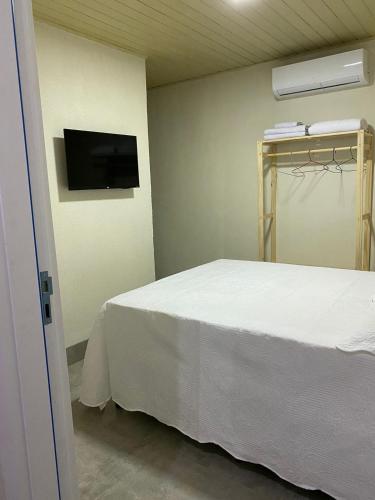 沙帕达-杜斯吉马朗伊斯Hospedagens Express I的卧室配有白色的床和平面电视。