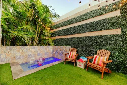 棕榈滩Privada Stays - Lofts with Private Pool and Oasis, near Eagle Beach的两把椅子和一个游泳池,位于带墙壁的庭院内